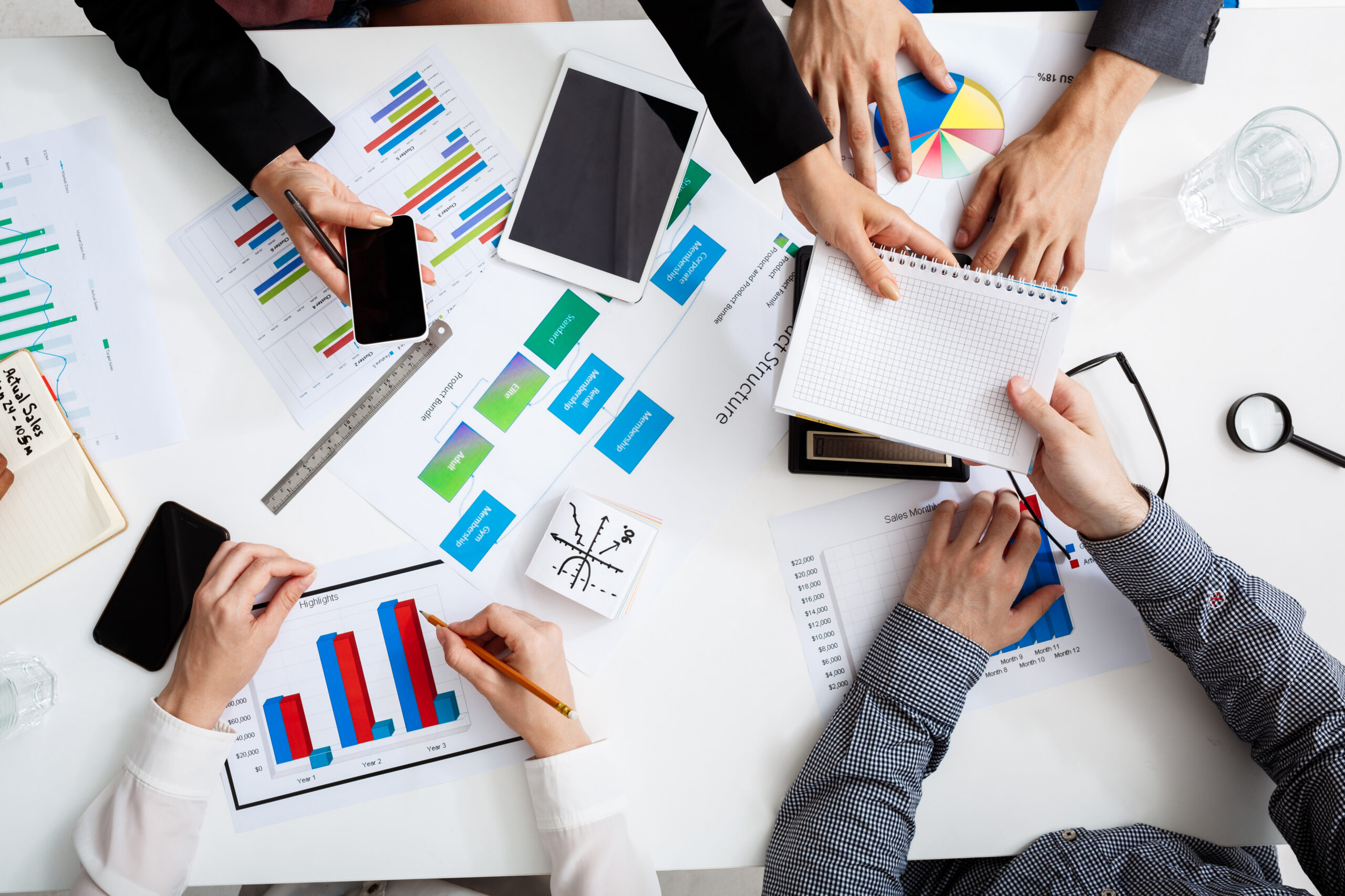Picture of businessmen's hands on white table with documents, coffee and drafts